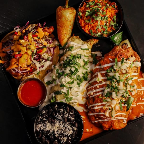Que Vida Tacos' Mexican platter with tacos, enchiladas, rice, beans, and a chili pepper.