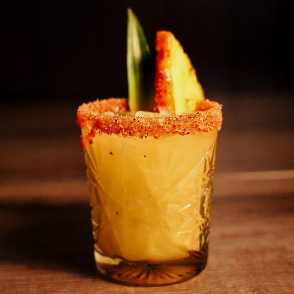 Que Vida Tacos' mango margarita with a chili-lime rim, garnished with pineapple and a green leaf.