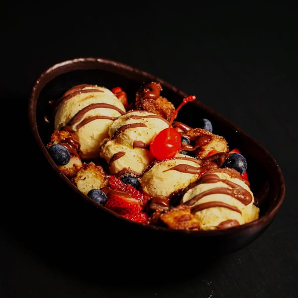 Que Vida Tacos' churro dessert with vanilla ice cream, chocolate drizzle, berries, and a cherry.